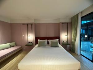 a bedroom with a large white bed and a window at Banlansuan Resort SHA Plus in Cha Am