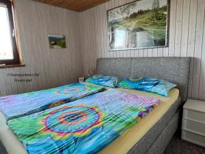 a bed with a colorful blanket on top of it at 2-1 - Raum - Ferienappartements Dieter Hoffmann Freudenstadt-Kniebis beim Nationalpark in Freudenstadt