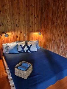 a bedroom with a blue bed with a basket on it at Viesuliškės Lakeside Glamping in Lakaja