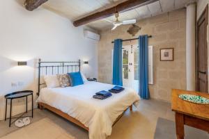 a bedroom with a large bed with blue curtains at Dar ta' Betta Farmhouse with private pool in Għarb