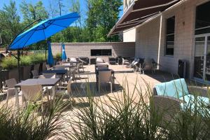 eine Terrasse mit Tischen, Stühlen und einem Sonnenschirm in der Unterkunft Courtyard by Marriott Montreal West Island/Baie D’Urfe in Baie-dʼUrfé