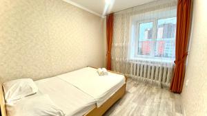 a small bedroom with a bed and a window at ГК ДОМ ДОСТЫК 3-комнатная в центре in Petropavlovsk