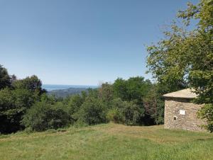 a stone building on top of a hill with trees at Faggio Rotondo in Neirone
