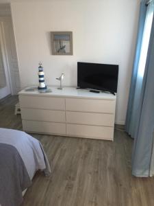 a bedroom with a dresser with a television on it at Cosy's'Plage in Kerderff