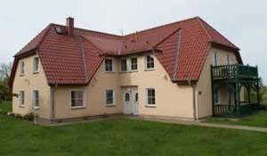 ein großes Haus mit rotem Dach in der Unterkunft Landsitz Rügen in Glowe