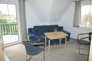 a living room with a blue couch and a table at Landsitz Rügen in Glowe