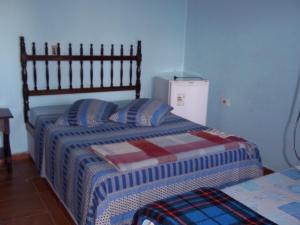 a bedroom with two beds and a refrigerator at Pousada Riacho Doce in Caraguatatuba