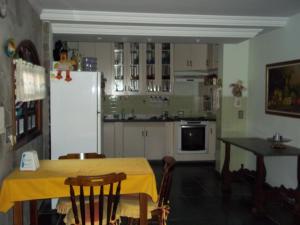 a kitchen with a table and a white refrigerator at Pousada Riacho Doce in Caraguatatuba