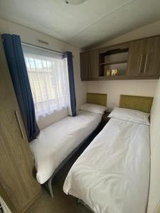 - 2 lits dans une petite chambre avec fenêtre dans l'établissement Serenity Holiday Home, à Saint Osyth