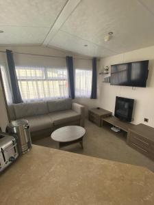 sala de estar con sofá y TV en Serenity Holiday Home, en Saint Osyth