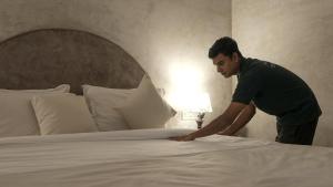 un hombre haciendo una cama en una habitación de hotel en Whiteflower Resort Morjim en Morjim