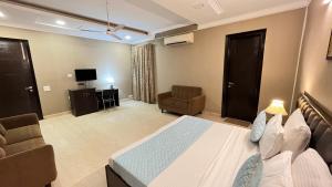 a bedroom with a bed and a couch and a television at Abode Residency Safdarjung Enclave Near U S Embassy Delhi in New Delhi