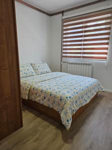 帕莱Casa bianca Pale的卧室内的一张床位,卧室内配有窗户和鲜花床罩