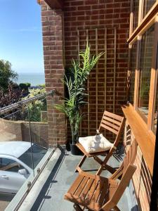 a balcony with two chairs and a potted plant at Stylish contemporary seaside holiday home with 5 bedrooms, sea view, parking and EV point in Kent