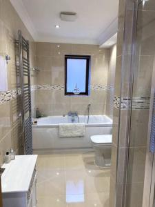 a bathroom with a tub and a toilet and a sink at Stylish contemporary seaside holiday home with 5 bedrooms, sea view, parking and EV point in Kent