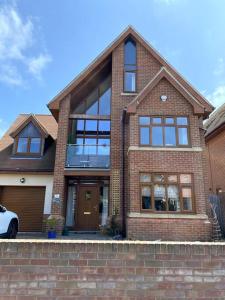 a brick house with a car parked in front of it at Stylish contemporary seaside holiday home with 5 bedrooms, sea view, parking and EV point in Kent