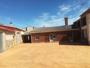 an old brick house with a dirt driveway at LA VILLA in Villarrín de Campos
