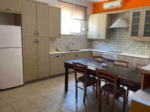 a kitchen with a table and chairs and a refrigerator at Anastasia's Apartment - Semi-basement Apartment (Rafaella Resort) in Kokóni