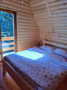 a bed in a log cabin with a large window at Planinska kuća in Žabljak