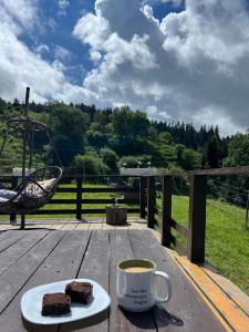 a cup of coffee and a piece of cake on a wooden table at Mitarbi Silence - cozy holiday cottages in mountains in Borjomi