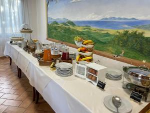 uma longa mesa branca com pratos e comida em Hotel Ristorante Le Querciolaie dei Ricci em Fonteblanda