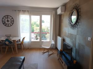 Sala de estar con reloj en la pared y TV en Centre, Soulages, Amphithéâtre - clim balcon parking, en Rodez