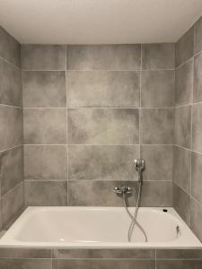 a bath tub in a bathroom with a tile wall at Mira Apart in Bad Säckingen