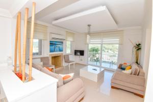 a living room with white furniture and a large window at Villa Rana The Royal Links Sarigerme in Ortaca