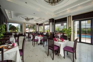 um restaurante com mesas brancas e cadeiras roxas em Golden Sun Hotel em Vientiane