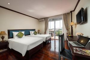 a bedroom with two beds and a desk with a laptop at Golden Sun Hotel in Vientiane