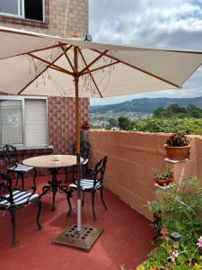a table and chairs under an umbrella on a patio at A Niñada in Marín +21 photos