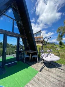 a house with a swing and a table on a deck at AGLAS CHALET in Moieciu de Jos
