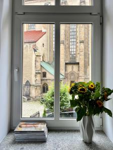 ein Fenster mit einer Vase aus Blumen und einer Kirche in der Unterkunft Apartamenty Wolwowicz in Jelenia Góra