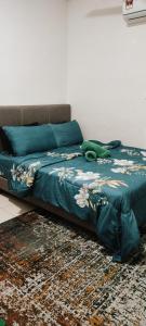 una cama con un edredón verde en una habitación en Amar & Nora Homestay en Ipoh