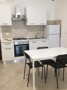 una cucina con tavolo bianco e alcune sedie di Villa Andalù Appartamenti a San Giovanni Rotondo