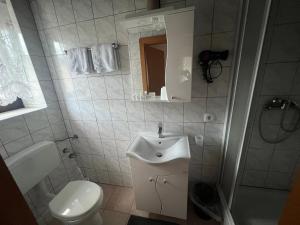 a white bathroom with a sink and a toilet at Gasthof Knezevic in Leoben
