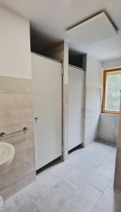 a bathroom with three doors and a sink at Mountain hut Dom pod Storžičem in Tržič