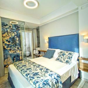 a bedroom with a large bed with a blue headboard at Piccolo Hotel in Terracina +123 photos