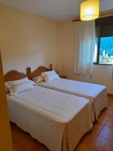 a bedroom with two beds with white sheets and a window at Casa Mercedes in Molinicos