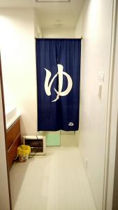 a room with a blue curtain with the ac logo on it at Fukuoka Guest House Jikka in Fukuoka