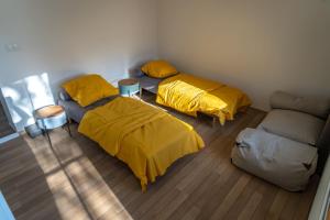 two beds with yellow sheets in a room with a couch at Raj v Slovenskom Raji 2 samostatné apartmány in Spišská Nová Ves