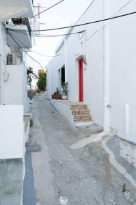 an alley with white buildings and a red door at Το παραδοσιακό σπίτι του Φτούλη! in Skiros