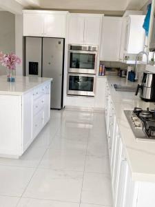 a white kitchen with white cabinets and a refrigerator at Home away from home in Christ Church