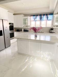 a white kitchen with a vase of flowers on a counter at Home away from home in Christ Church