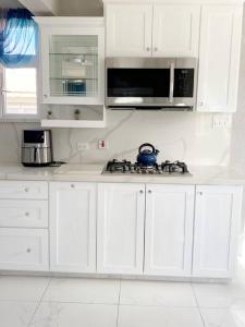 a white kitchen with white cabinets and a microwave at Home away from home in Christ Church