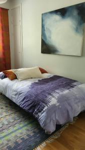 1 cama en un dormitorio con una pintura en la pared en Peaceful and beautiful apartment in Hämeenlinna, en Hämeenlinna