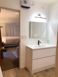 baño con lavabo, espejo y cama en Alpine View Lodge, en Wanaka