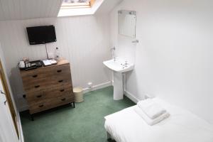 um quarto com um lavatório, uma cama e uma televisão em Harbour Guest House em Tobermory