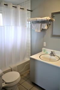 a bathroom with a toilet and a sink and a tub at Campbell's Motel Scottsburg in Scottsburg