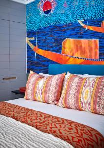 a bed with pillows and a painting of boats at Pineapple House Boutique Hotel in Cape Town